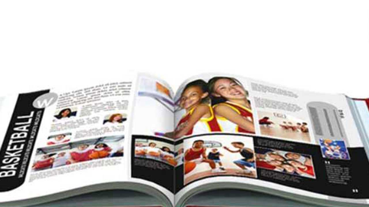 An open magazine displaying photos and articles about basketball, including images of children playing, smiling, and enjoying a Yearbook Signing party.